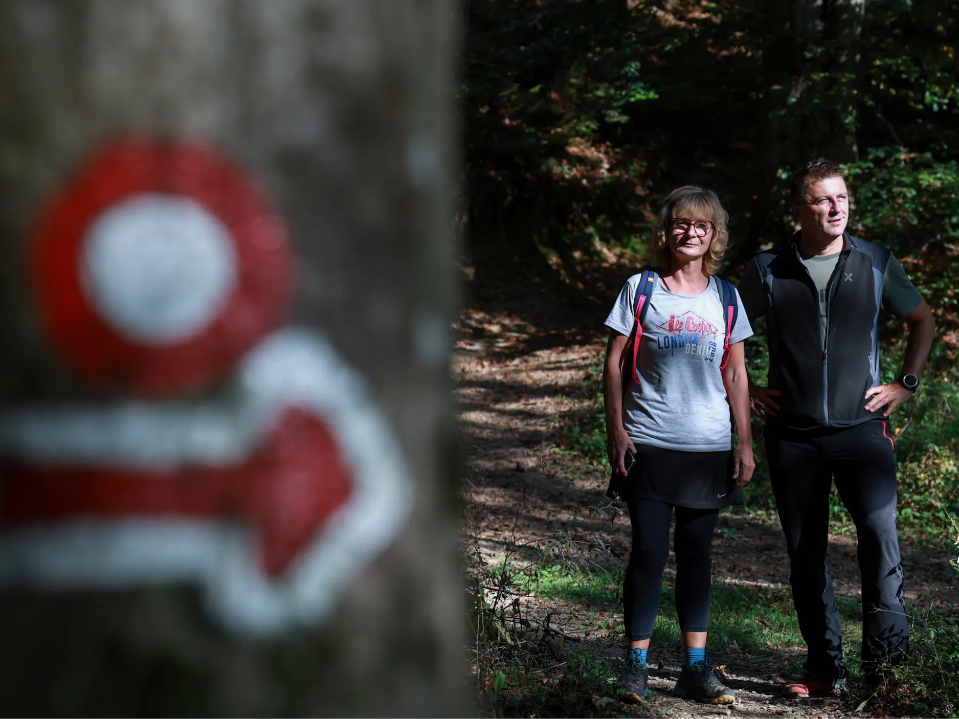 Ženska in moški v športnih oblačilih stojita na gozni poti